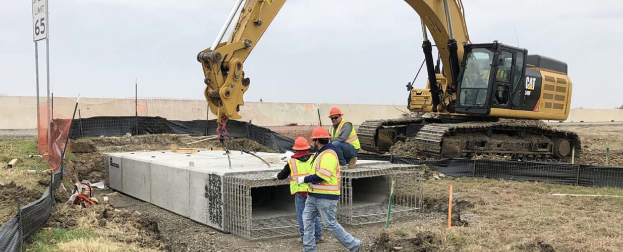 excavator lifting beams with construction workers at IH 35E